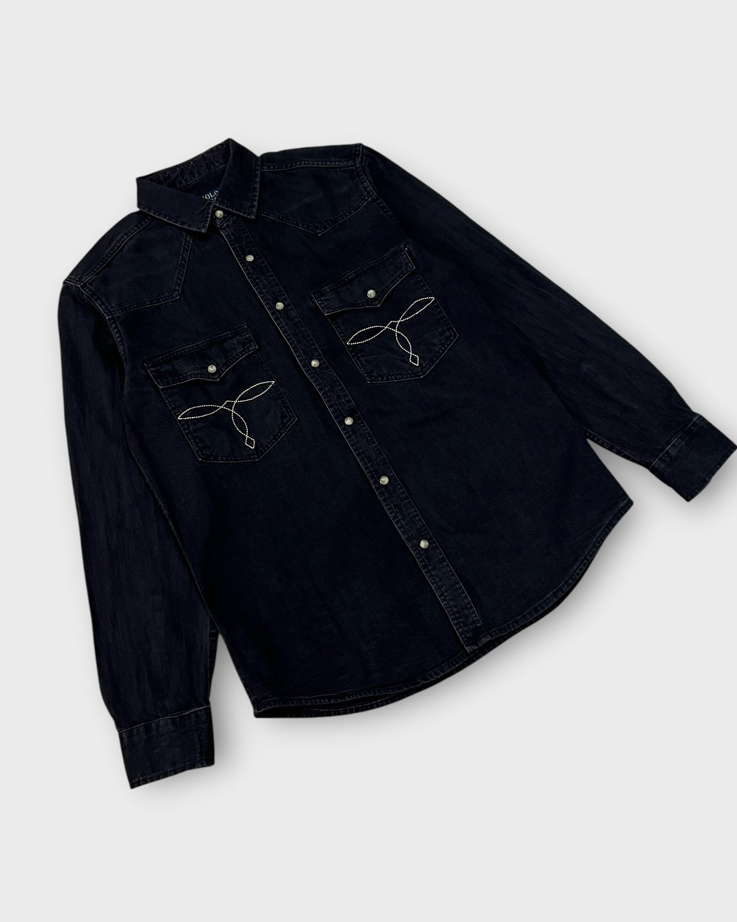 Black denim shirt with embroidered designs on a white background